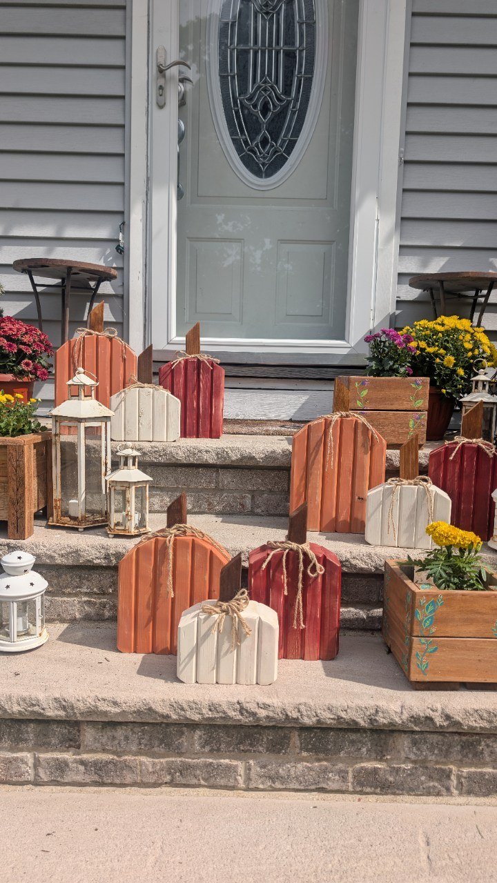 Handmade wooden pumpkin sets and wooden flower planters displayed on front porch steps