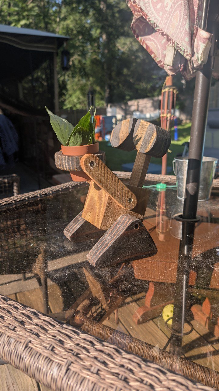 Artisan robot-style wooden planter holding a flower pot